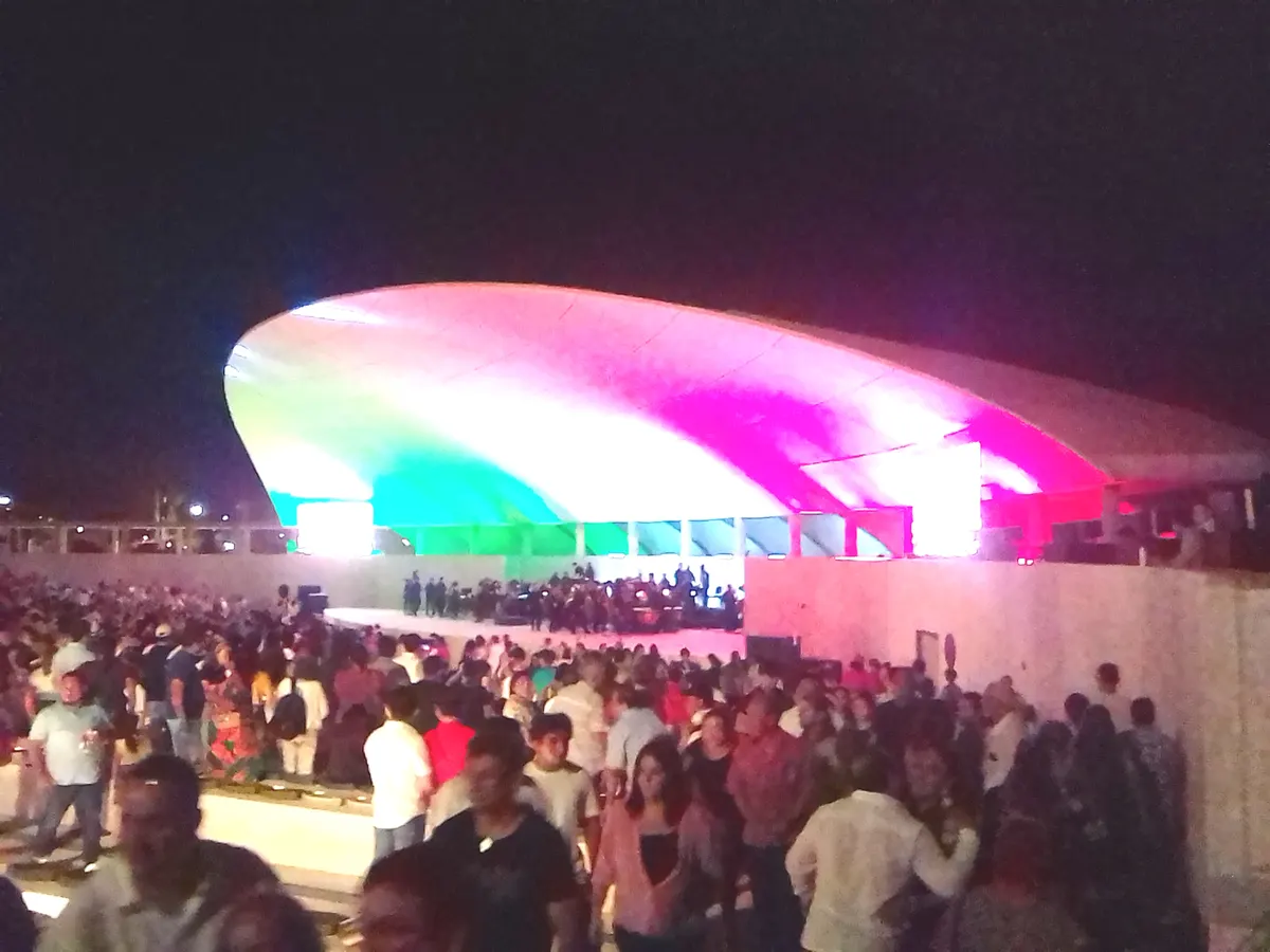 Público lleno frente al escenario iluminado del anfiteatro de La Plancha durante un concierto nocturno